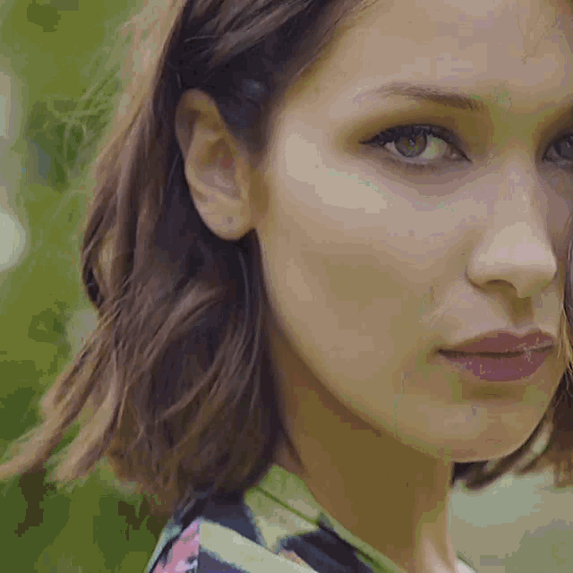 a close up of a woman 's face with a floral shirt on