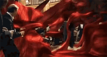 a group of people in red dresses are dancing in a room with a chandelier .
