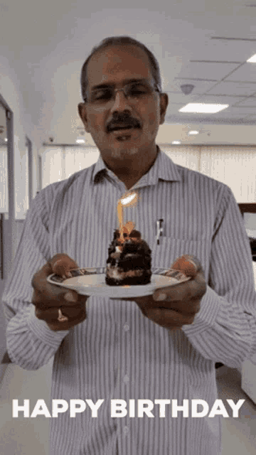 a man in a striped shirt is holding a birthday cake with a lit candle and the words happy birthday below him
