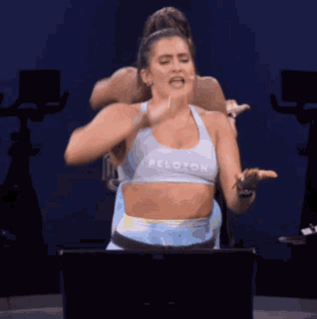 a woman wearing a peloton top is on a bike