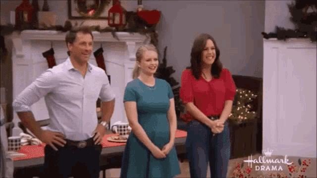 a man and two women are standing in front of a fireplace in a hallmark drama advertisement