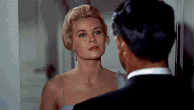 a woman in a blue dress looks at herself in the mirror