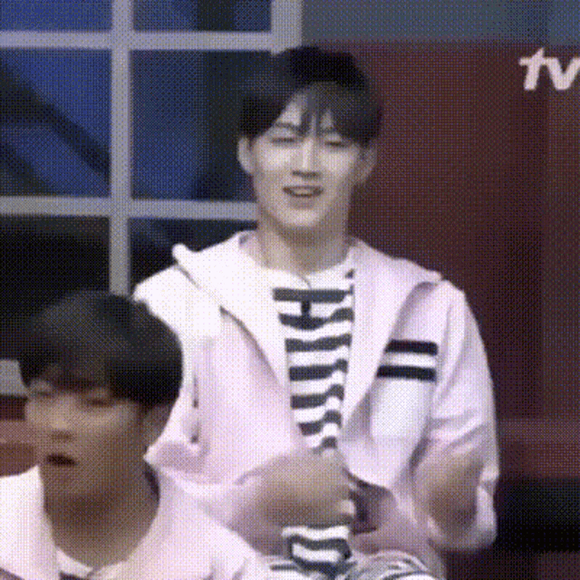 a man in a pink jacket and striped shirt is sitting next to another man in a pink jacket and striped shirt .