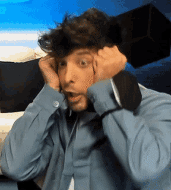 a man in a blue shirt and tie is covering his ears