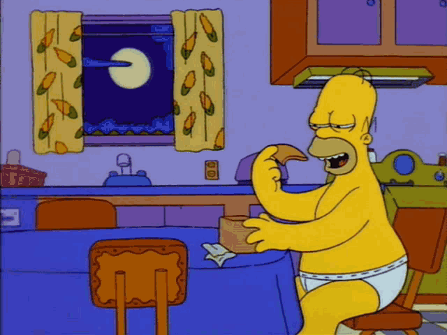 homer simpson is sitting at a table eating a piece of bread