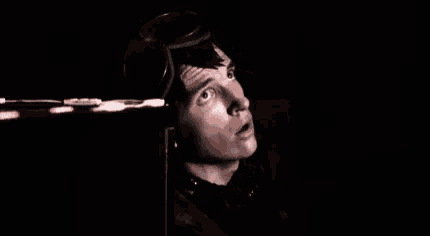 a man wearing a goggles is looking up in the dark .