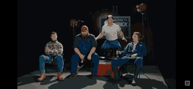 a group of men sit in front of a sign that says " welcome to crack "