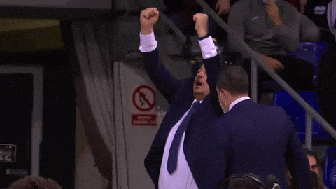 a man in a suit and tie holds his arms in the air