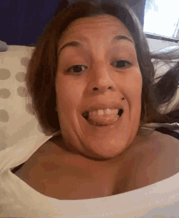 a woman is sticking her tongue out while laying on a bed
