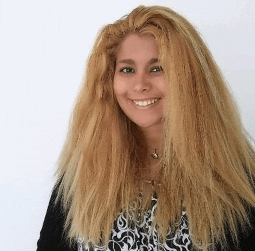 a woman with long blonde hair is smiling and wearing a black and white shirt