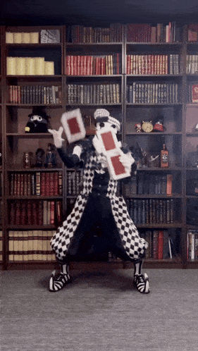 a man in a black and white checkered costume is holding a red card