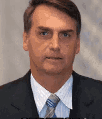 a man in a suit and tie is looking at the camera and making a funny face .