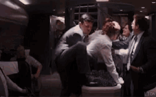 a man in a suit is being held by another man in a limo .