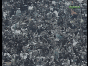 a crowd of people are gathered in a stadium with a green sign that says centretv8