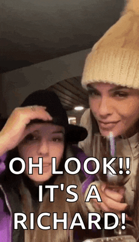 two women are standing next to each other and one is holding a glass of wine .