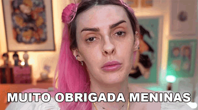 a woman with pink hair says muito obrigada meninas in front of her face