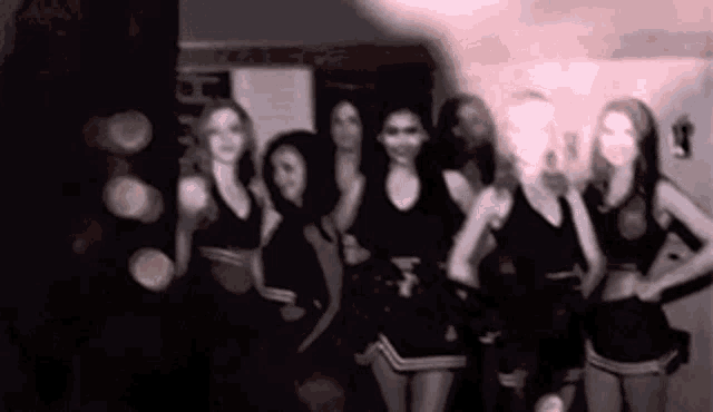 a group of cheerleaders standing next to each other in a locker room .