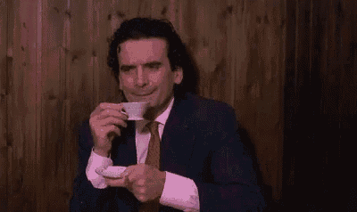a man in a suit and tie is drinking from a cup of coffee .
