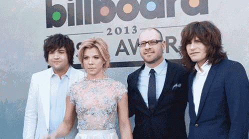a group of people posing in front of a billboard that says 2013 award