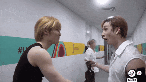 two men are standing next to each other in a hallway with a sticker that says talker