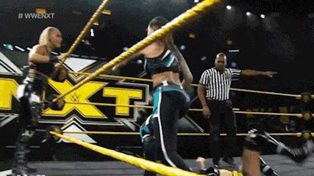 two women are wrestling in a wrestling ring with a referee in front of a sign that says nxt