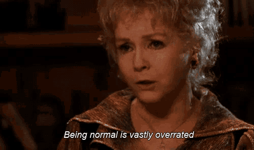 a woman is sitting in a dark room and says `` being normal is vastly overrated '' .