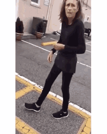 a woman in a black shirt and black pants is walking down the street .
