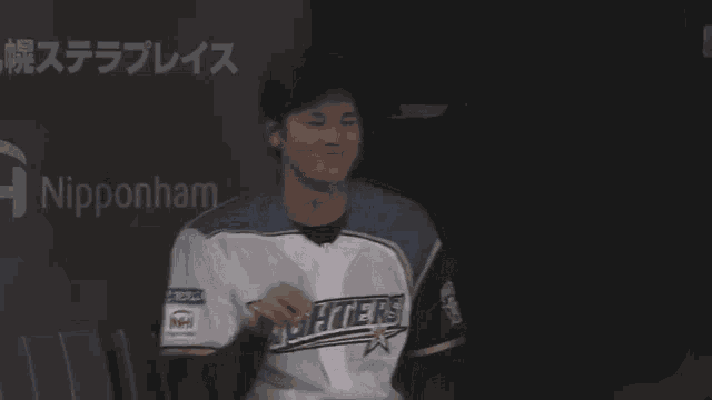 a man wearing a nipponham fighters jersey smiles