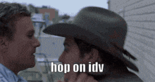 two men in cowboy hats are kissing each other .