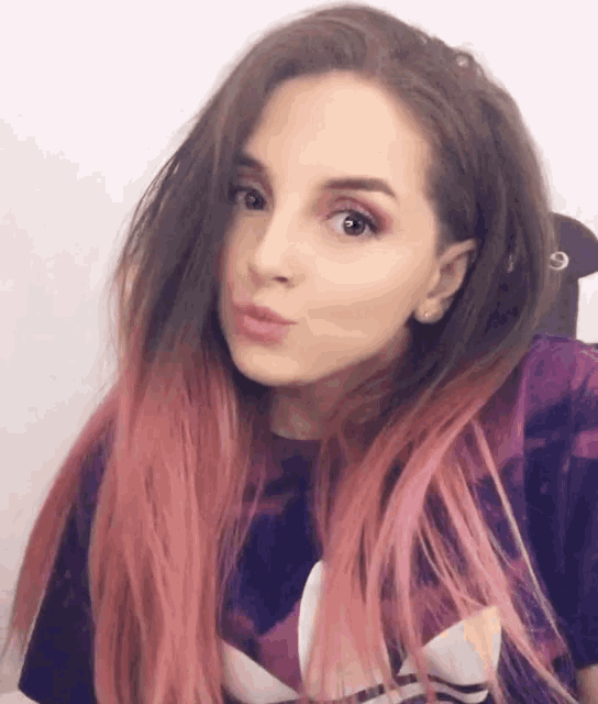 a woman with pink hair wearing a purple adidas shirt