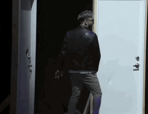 a man in a black leather jacket is standing in a doorway