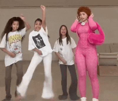 a group of young girls are dancing together in a room . one girl is wearing a pink outfit .