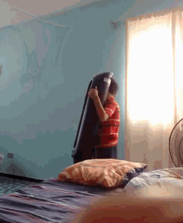 a man in a red and white shirt is holding a suitcase in a bedroom