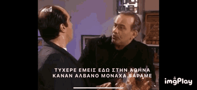two men are standing next to each other in a room and talking in a foreign language .