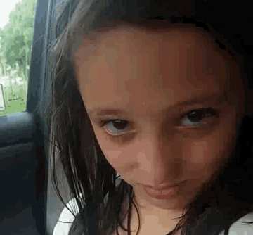 a close up of a young girl 's face in a car window