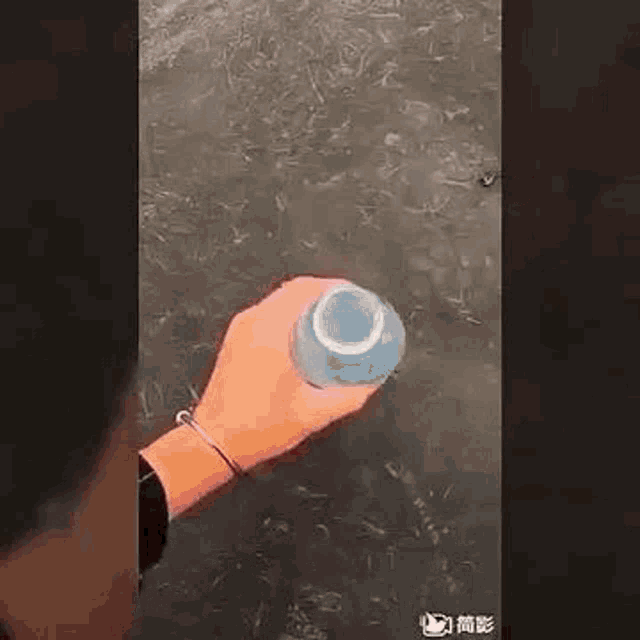 a person is holding a bottle of water in their hand in the water .