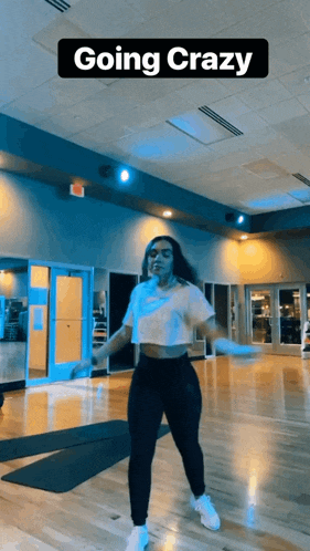 a woman is dancing in a gym with the words going crazy behind her