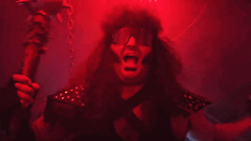 a man wearing sunglasses and a hat is screaming in a red light