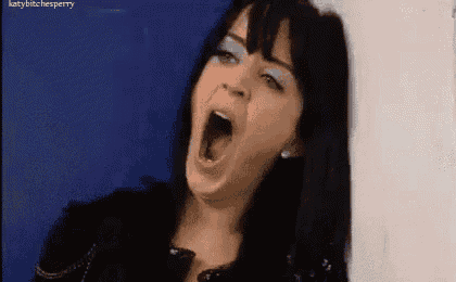 a woman is yawning with her mouth wide open against a blue wall .
