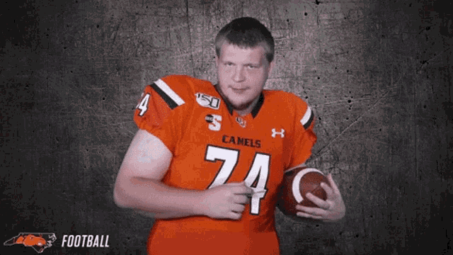 a man wearing an orange jersey with the number 74 on it holds a football