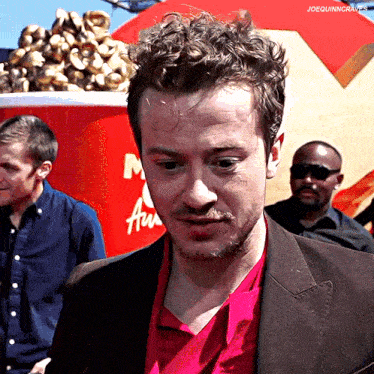 a man in a red shirt is standing in front of a mcdonald 's cup of popcorn