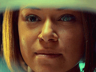 a close up of a woman 's face with a reflection of her eyes in a mirror .