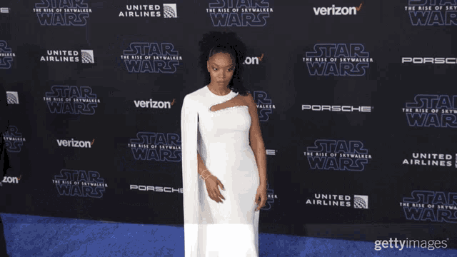 a woman in a white dress is standing in front of a star wars advertisement
