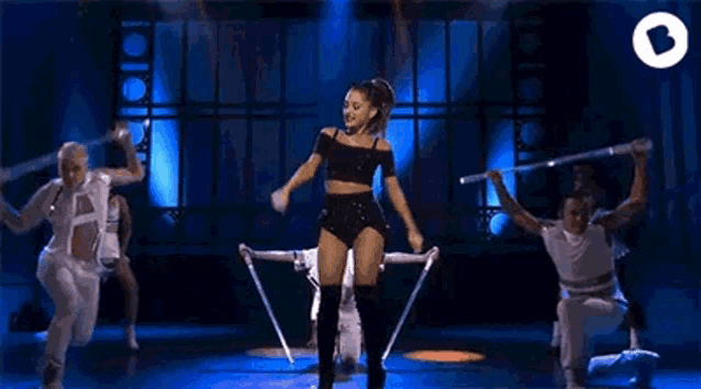 a woman is dancing on a stage with a group of dancers behind her .