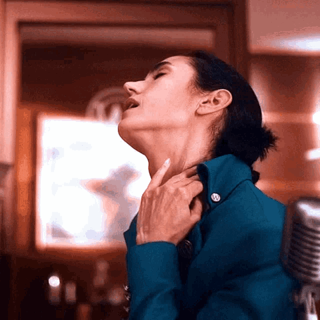 a woman in a blue jacket is holding her neck