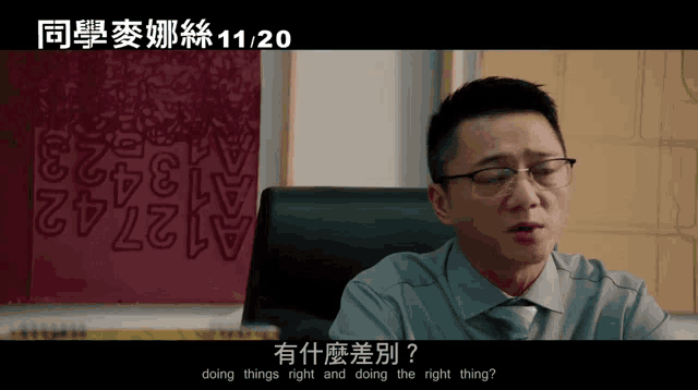 a man with glasses is sitting in front of a wall with numbers on it and the date 11/20