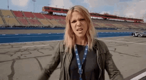 a woman is standing in front of a race track and making a face .