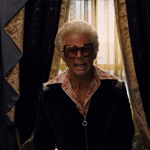 a man with white hair wearing sunglasses and a jacket