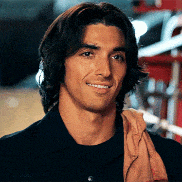 a man with long hair and a towel around his neck is smiling