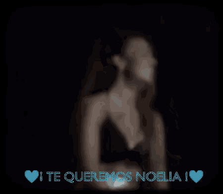 a woman in a black top is smiling in the dark with the words te queremos noelia above her